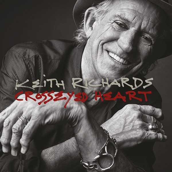 Black and white photo of Keith Richards smiling, wearing a hat and jewelry, with the album title Crossed Eyed Heart in red and white text.