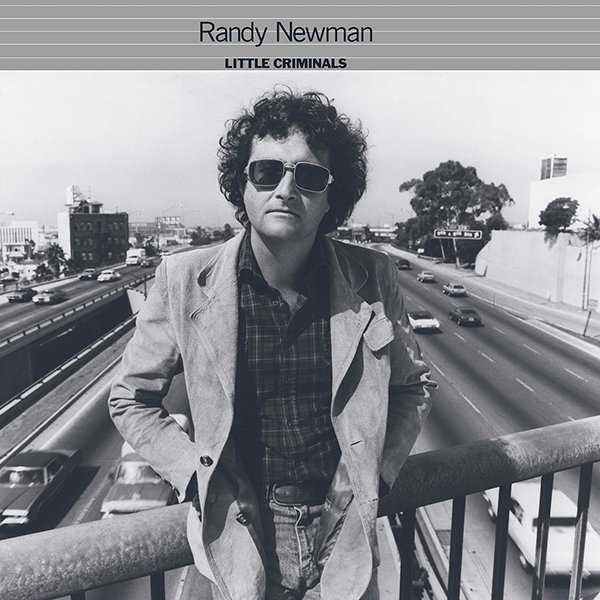Black and white photo of a man with curly hair and sunglasses standing on a bridge over a busy highway, with the text 'Randy Newman Little Criminals' above.
